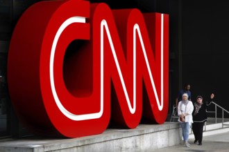 Large red CNN logo on a building, people walk past, Atlanta, Georgia, USA