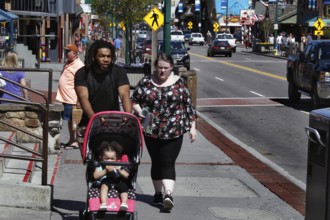 Family with stroller walking down the sunny main street of Gatlinburg, Gatlinburg, Tennessee, USA