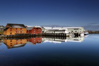 Warehouses in Vardø harbour are reflected in still water, Vardø, Finnmark, Norway