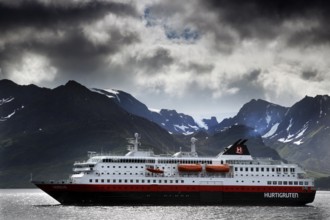 Hurtigruten ship in Øksfjord in front of a majestic mountain panorama, Øksfjord, Norway