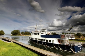 Passenger ship in the Göta Canal at a dock under a cloudy sky, mountain, Sweden