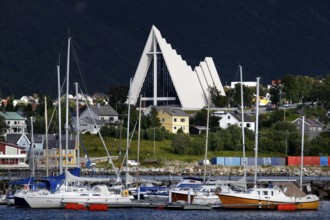 Ishavskatedralen towers over boats and houses in Tromsdalen, Tromsø, Troms, Norway