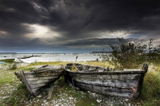 Dilapidated fishing boats on the stormy coast of Gotland under dramatic skies, Gotland, Sweden