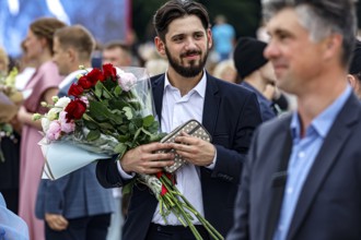 A man with a bouquet of flowers is enjoying the graduation ceremony in a festive atmosphere,