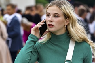 Young woman talking on the phone during a high school graduation ceremony on Cathedral Square,