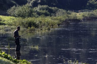An angler stands patiently on the banks of the Nemunas River in Vilkija, Vilkija, Lithuania