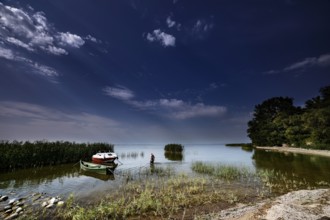 Boats on calm water with wide skies in the Curonian Lagoon near Vente, Vente, Lithuania