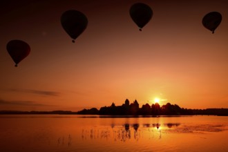 Balloons float in the morning sky over Trakai Castle at sunrise, Trakai, Lithuania