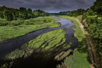 Musa river with green surroundings under cloudy sky, Bauska, Latvia