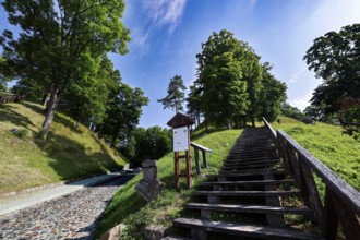 Wooden staircase leads through wooded hills in Veliuona under blue sky, Veliuona, Lithuania