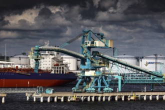 View of a harbor with cranes and a ship, dramatic clouds in the background, Ventspils, Latvia