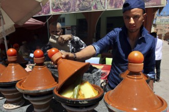 Traditional Moroccan cuisine with several brown tagine pots in a restaurant, El Kelâa m'Gouna,