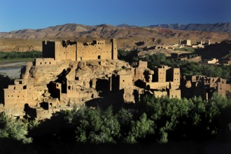 Clay buildings of the Kasbah in the Valley of Roses with surrounding mountain landscape under blue