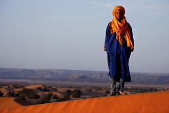 Bedouin in traditional dress stands on a sand dune near Erg Chebbi, Erg Chebbi, null, Morocco