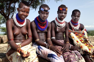 Four young woman in traditional clothing and jewelry in the village of Murle, Murle, Ethiopia