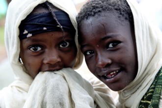 Two children wearing traditional clothes smile during a church service