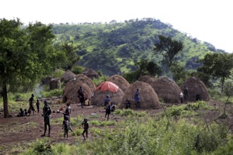 Several Morsi huts in a green valley with mountains in the background, Mago National Park, null,