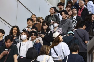 People on an escalator in Shibuya Station, partly wearing face masks, Tokyo, Japan