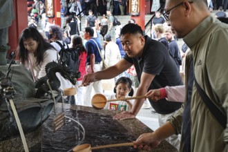 People purify themselves at a purification well in Senso-ji Temple, Tokyo, Japan