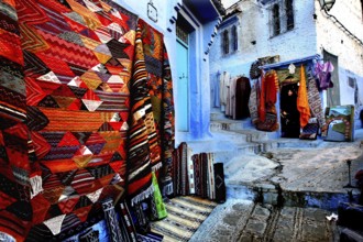 Colourful carpets and crafts in the blue streets of the medina of Chefchaouen, Chefchaouen, Morocco
