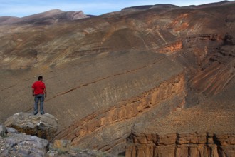 A person wearing a red jacket looks at the Dadès Canyon with impressive rock formations, Dadès