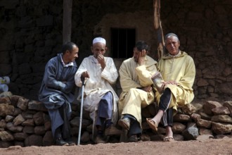 Four men in traditional clothes sit sociably on a wall in Achaouikh, zero