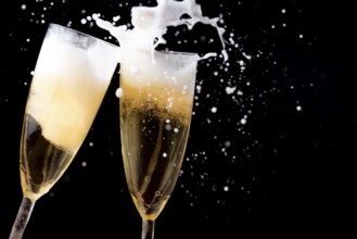 Two sparkling champagne glasses with foam against a dark background