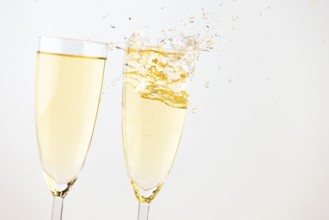 Two champagne glasses with sparkling drink against a bright background