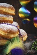 Close-up of Berliners with powdered sugar and pearl necklaces, colorful carnival atmosphere