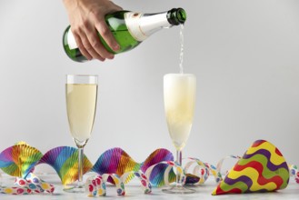Sparkling wine is filled into glasses surrounded by colorful streamers, carnival
