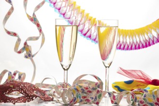 Two champagne glasses surrounded by decorative colorful streamers, carnival