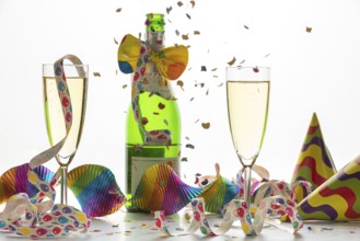 Champagne glasses and bottle surrounded by streamers and confetti, carnival