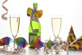 Two champagne glasses and a bottle surrounded by colorful streamers and hats, festive atmosphere,