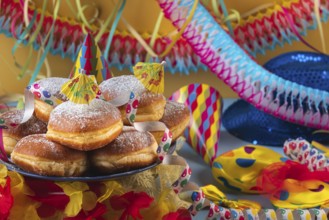 A plate of donuts surrounded by colorful party hats, streamers and garlands, carnival