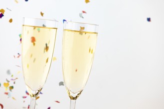 Two champagne glasses with colorful confetti in the background
