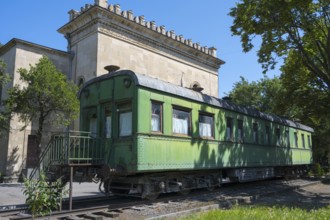 Old green railroad car in front of historic building and trees, Stalin's personal railroad wagon,