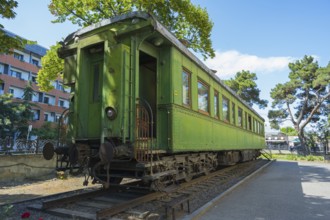Green historic train car on rails between trees in an urban environment, Stalin's personal railroad