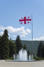 Large Georgian flag flying over a fountain in front of a hilly landscape, Stalin Park, Gori, Inner