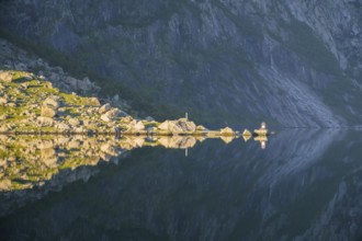 Sunny rocky landscape reflected on the calm water surface of Lysefjord, calm water reflects rocks