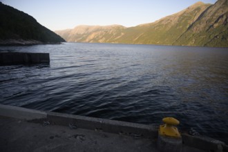 Songesand, Rogaland Municipality, Norway, coastline with calm water and shade on mountains at dusk