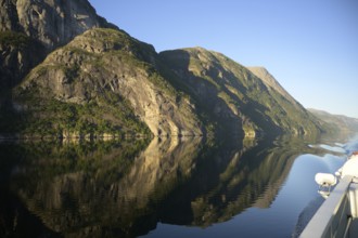 A boat sails along an orderly and peaceful Lysefjord surrounded by massive rock walls, Lysefjord,
