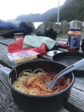 Rogaland Municipality, Norway, spaghetti with sauce on a wooden table in a rocky outdoor setting