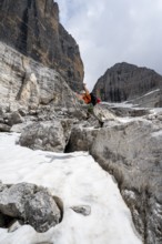 Mountaineer jumping off a rock into the snow, Camosci Valley, Brenta Mountains, Brenta-Adamello