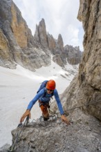 Mountaineer climbs on a steep rock face in the Via Ferrata dell'Ideale via ferrata, spectacular