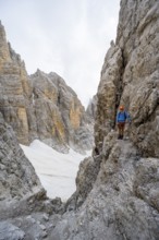 Mountaineer climbs on a steep rock face in the Via Ferrata dell'Ideale via ferrata, spectacular