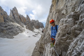 Mountaineer climbs on a steep rock face in the Via Ferrata dell'Ideale via ferrata, spectacular