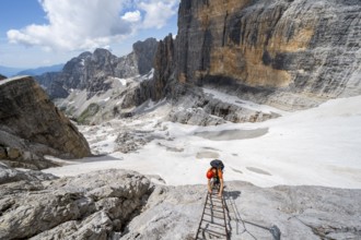 Mountaineer climbs on a ladder in the Via Ferrata Brentari via ferrata, spectacular mountain