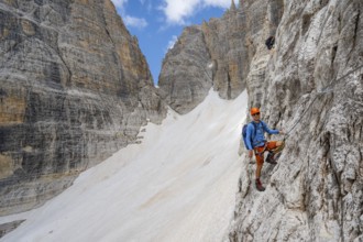 Mountaineer climbs on a steep rock face in the Via Ferrata Brentari via ferrata, spectacular