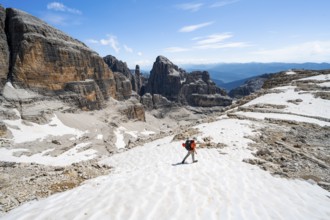Mountaineers in a snowfield on the Sella della Tosa, mountain landscape with steep cliffs, Brenta