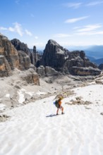 Female mountaineer in a snowfield on the Sella della Tosa, mountain landscape with steep cliffs,